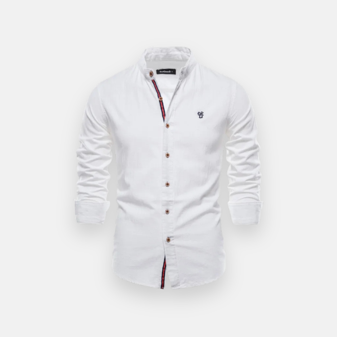 Camisa social branca de manga longa com detalhes em tecido listrado na parte interna da abertura frontal, botões marrons e um bordado pequeno azul no lado esquerdo do peito.