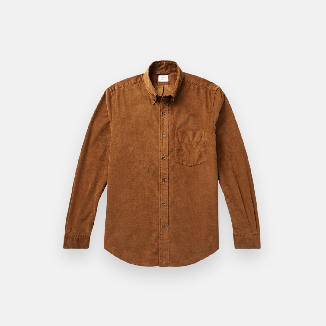 Camisa de manga longa marrom, confeccionada em tecido de veludo cotelê, com bolso frontal no lado esquerdo do peito, botões escuros e gola clássica, ideal para um estilo casual e elegante.