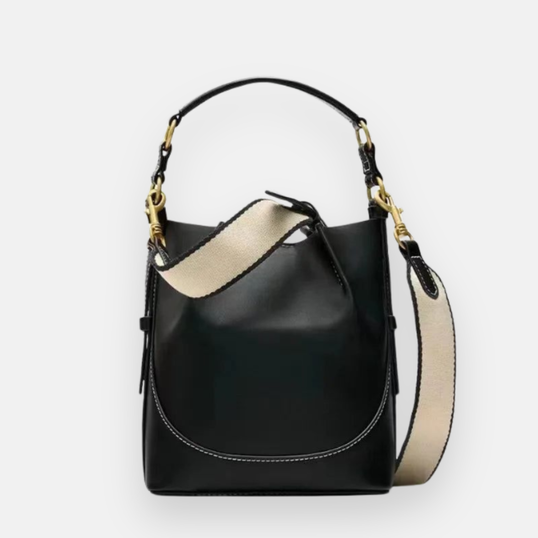 Bolsa bucket preta com acabamento em couro liso, costura contrastante branca, alça curta em couro e alça longa ajustável em tecido com detalhes dourados, ideal para um estilo casual e sofisticado.